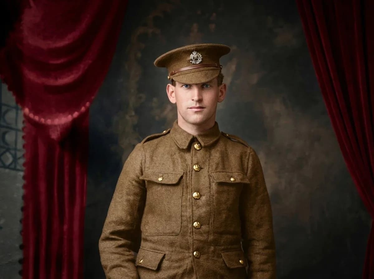 Young WWI soldier in khaki uniform and military cap against dark backdrop with red velvet curtains, formal portrait style