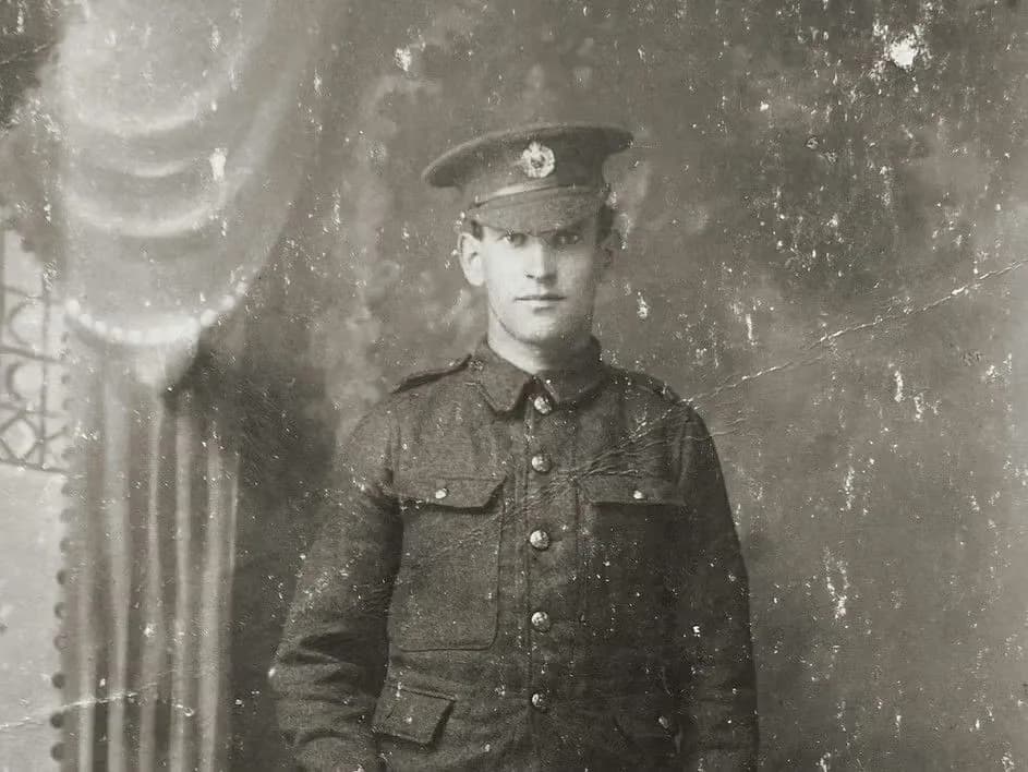 Young soldier in WWI military uniform with cap and buttons, vintage black and white portrait photograph