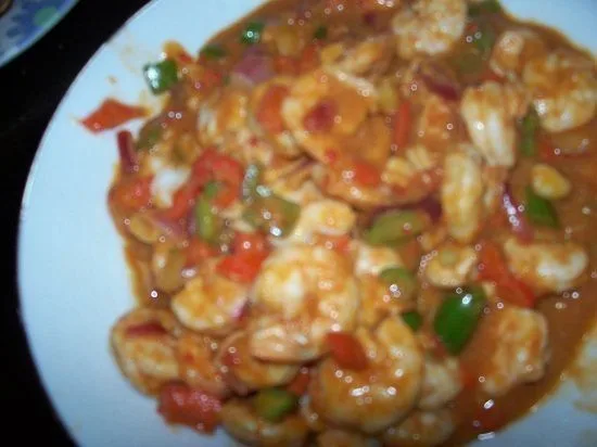 Shrimp stir-fry with red bell peppers, green peas, and glossy brown sauce on white plate, Asian seafood dish