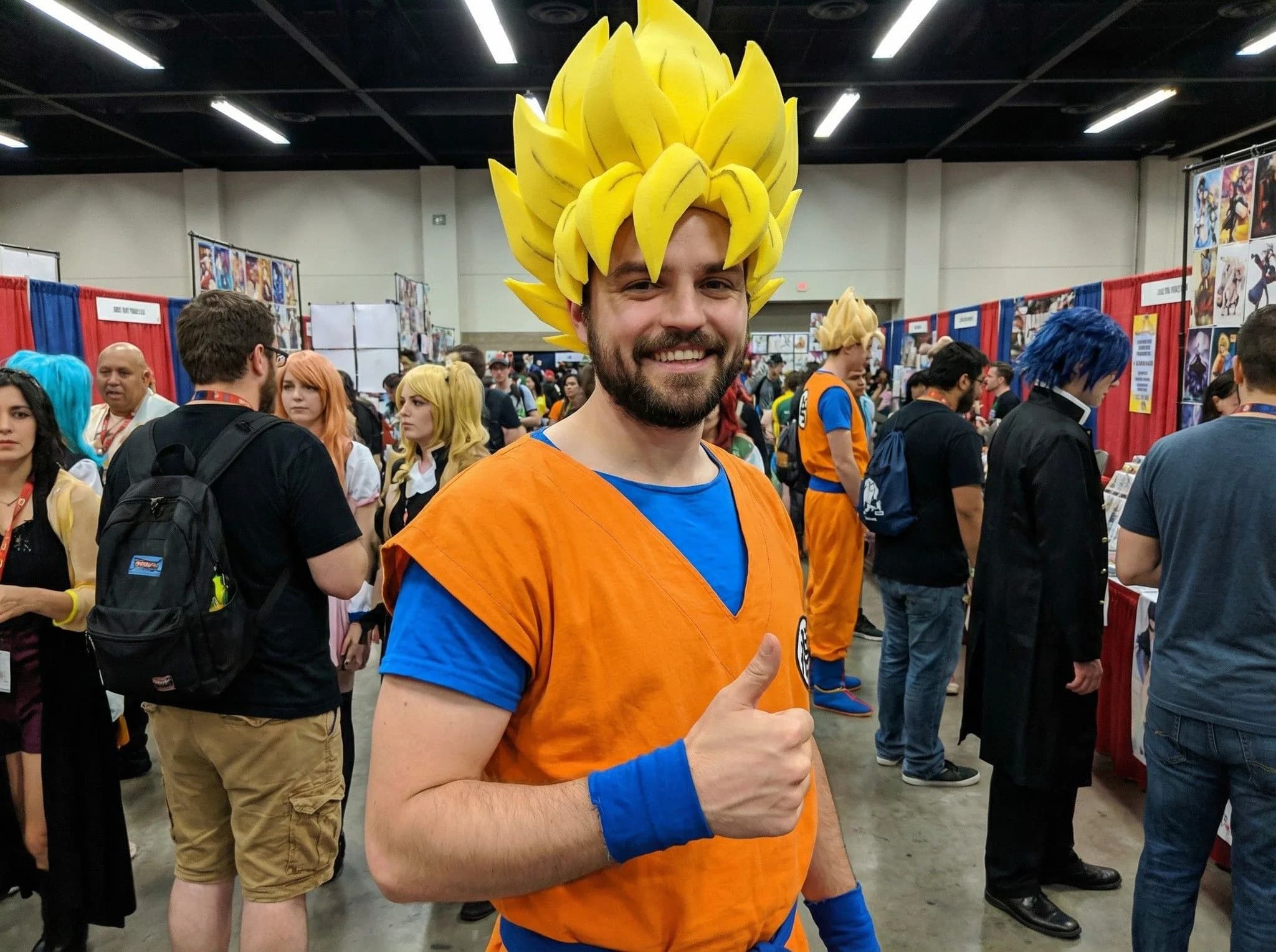 Cosplayer dressed as Goku from Dragon Ball Z with iconic yellow Super Saiyan hair at anime convention