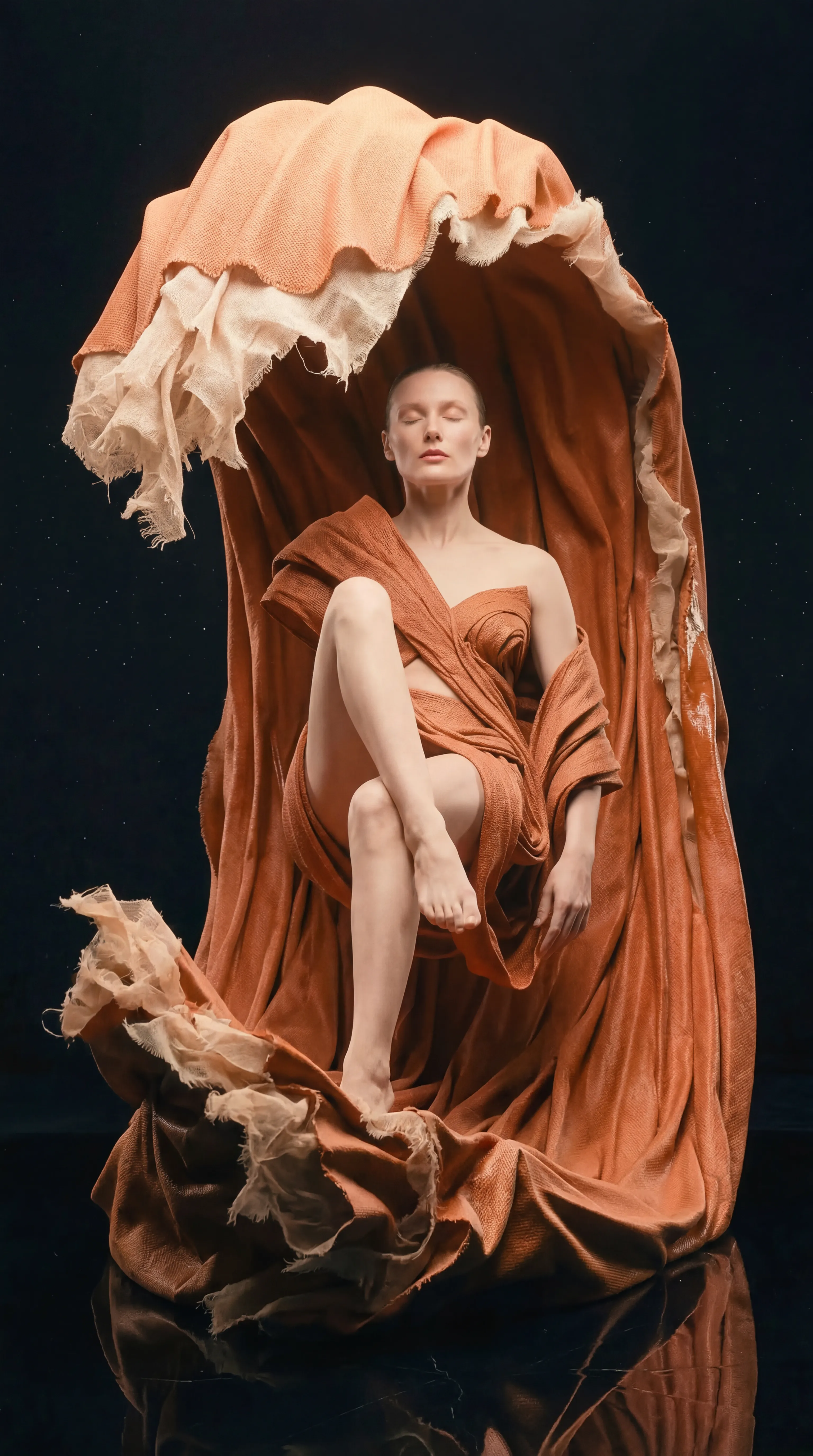 Woman floating in a swirl of flowing orange fabric