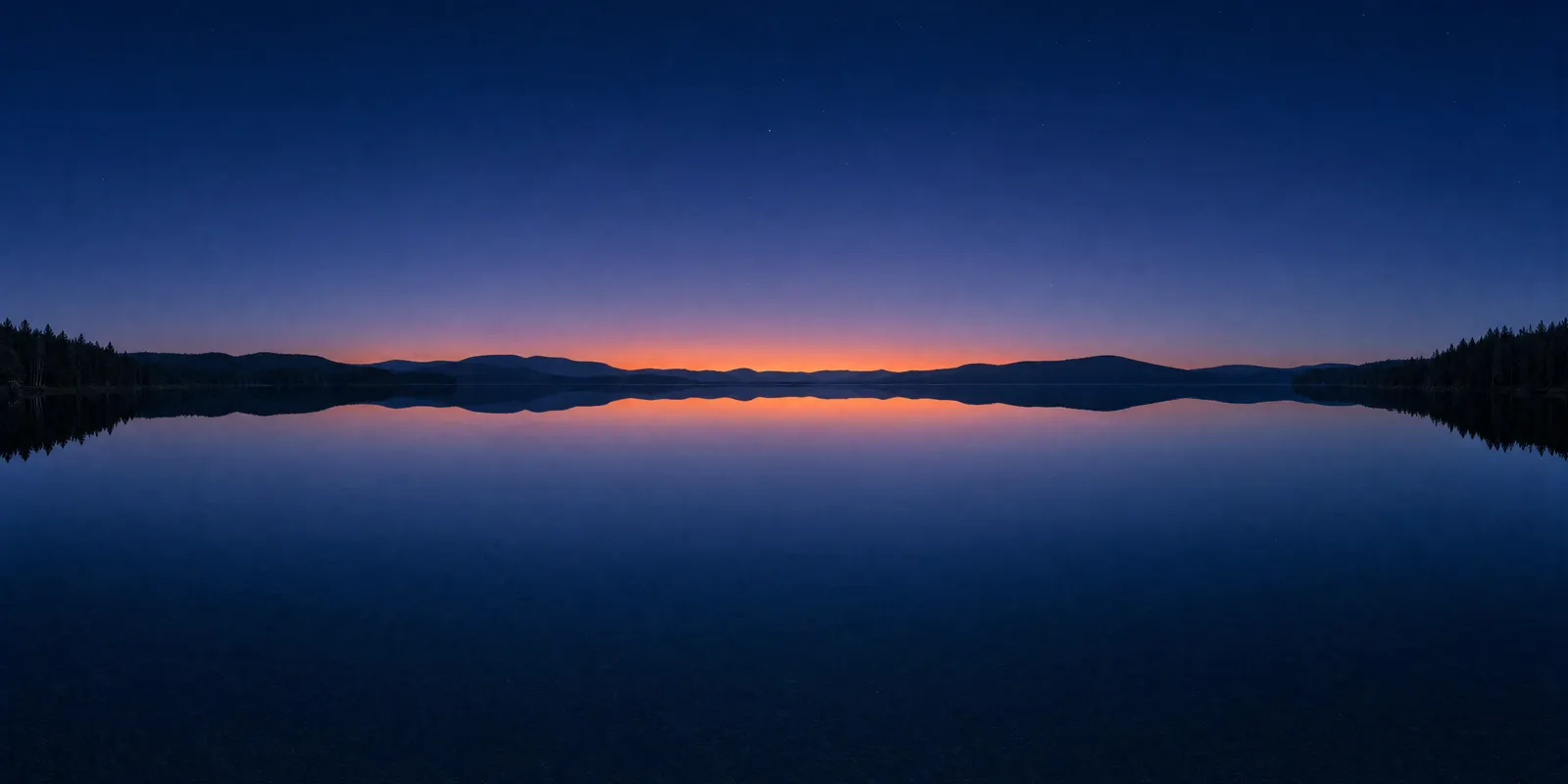 The same lake panorama at dusk, deep blue with an orange afterglow on the horizon